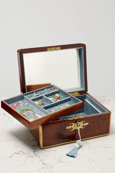 an open wooden box with jewelry in it on a table next to a tassel