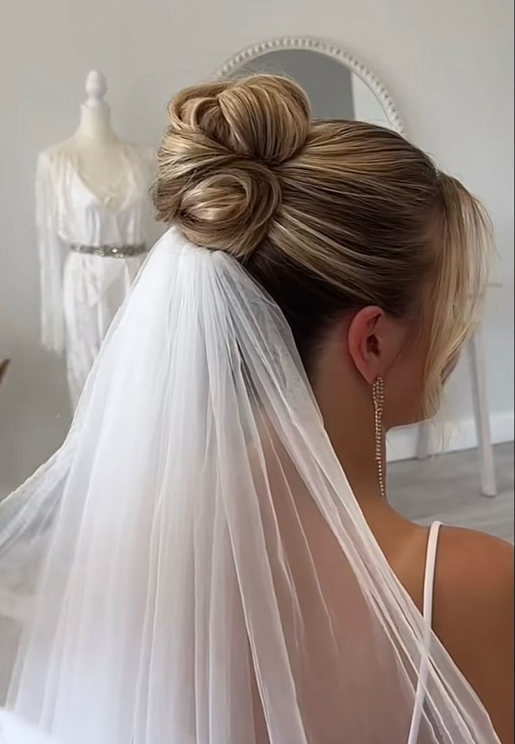 a woman wearing a wedding veil with her hair in a bun