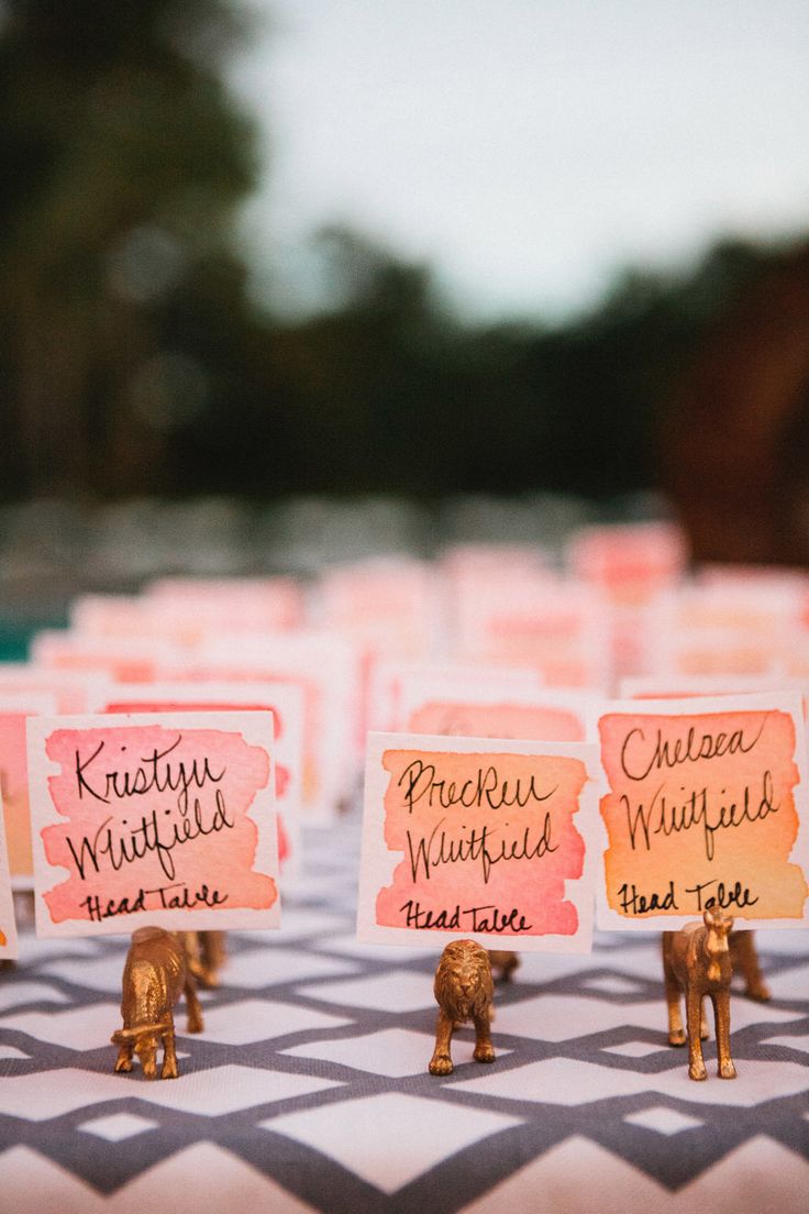 place cards with elephants on them sitting on a checkered tablecloth covered in pink and yellow