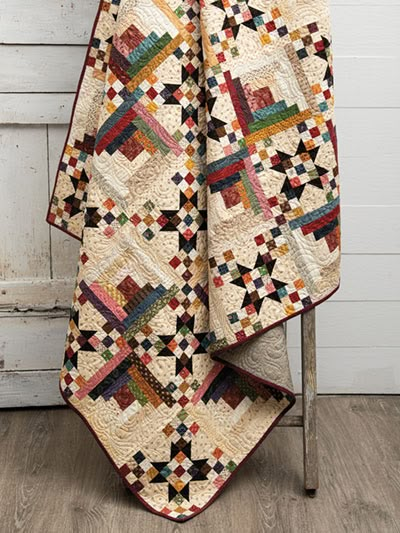 a quilt is hanging on a chair in front of a white wall and wooden floor