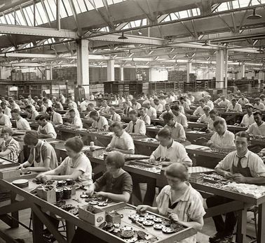 an old factory filled with lots of people working on machines and trays full of food