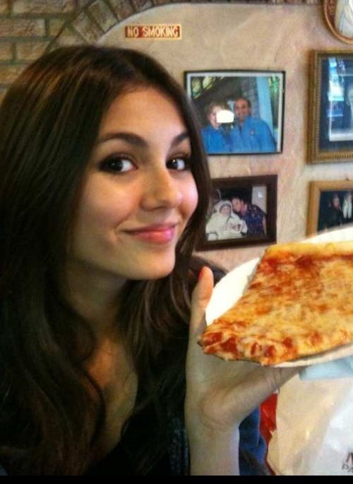 a woman holding up a slice of cheese pizza