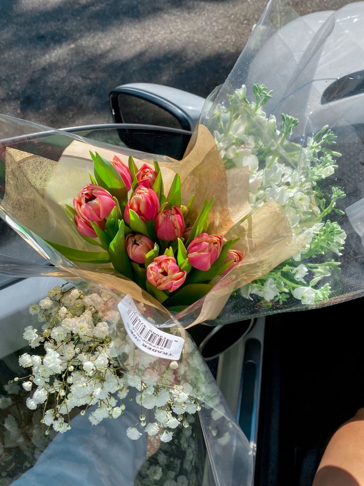 a bouquet of tulips and baby's breath wrapped in plastic