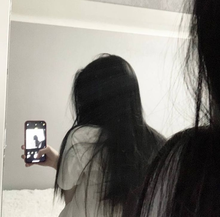 a woman taking a selfie in front of a mirror with her hair blowing back