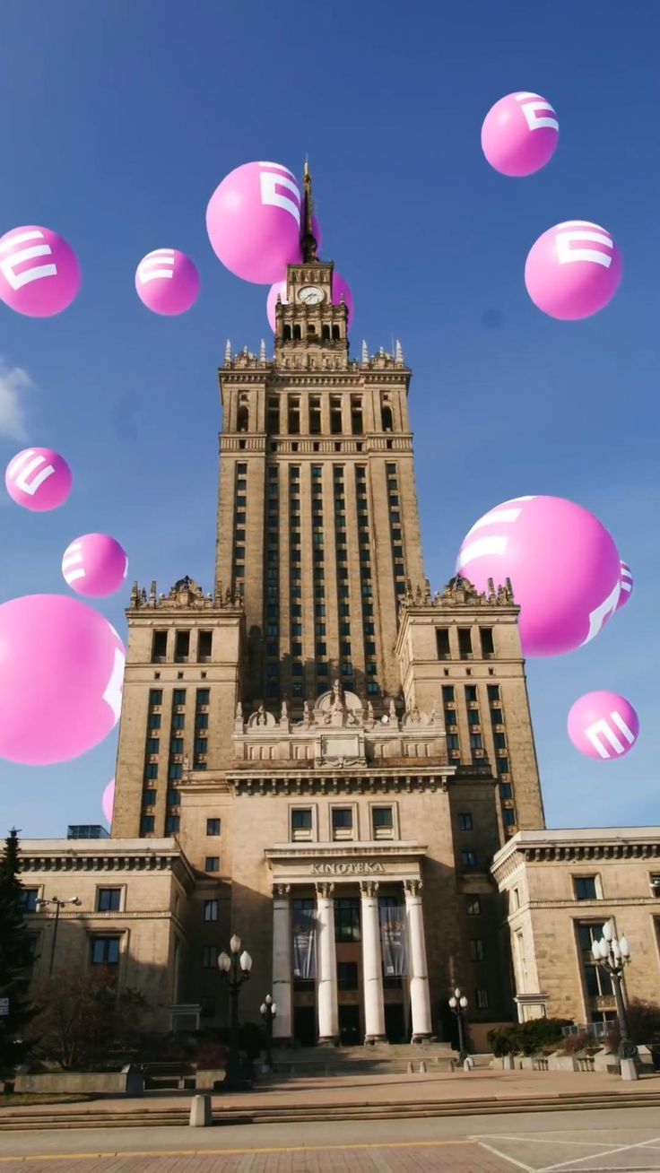 pink balloons are floating in the air near a large building with columns and pillars on it