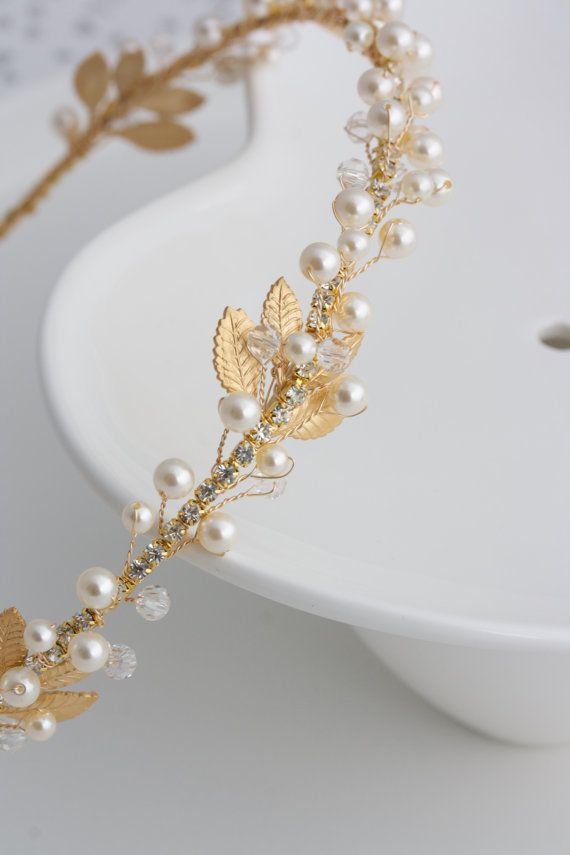 a white plate with a gold leaf and pearl headpiece on it's side