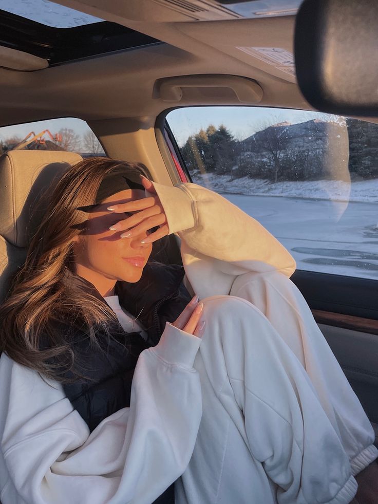 a woman sitting in the back seat of a car holding her hands to her face