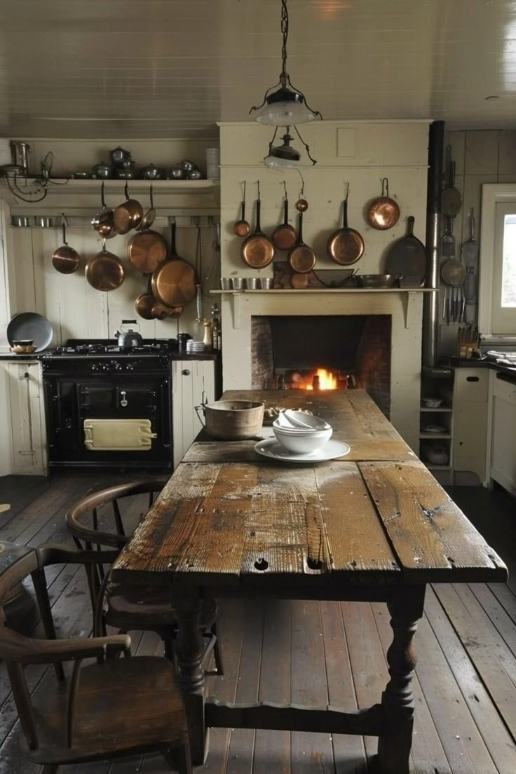 an old fashioned kitchen with a fireplace and wooden table in front of the fire place