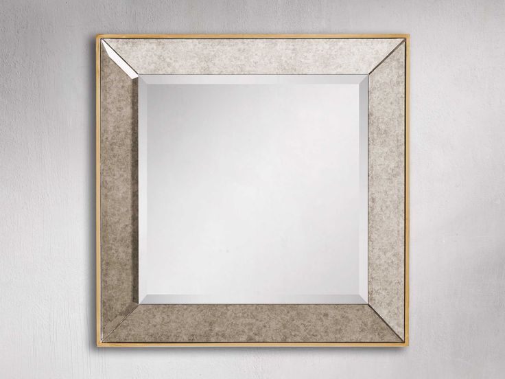 a square mirror hanging on the wall with a gold border around it and a white background