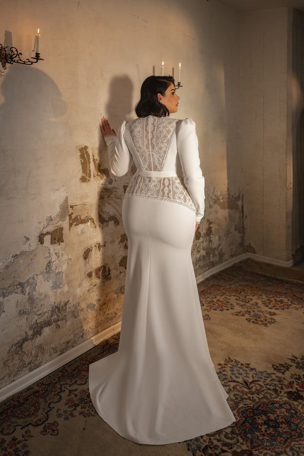 a woman in a white wedding dress standing next to a wall with candles on it