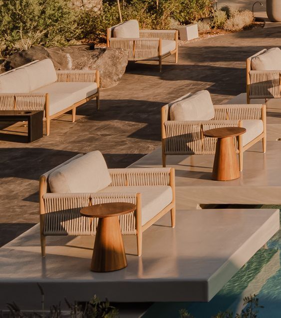 some chairs and tables near a pool in the day time with no one around them