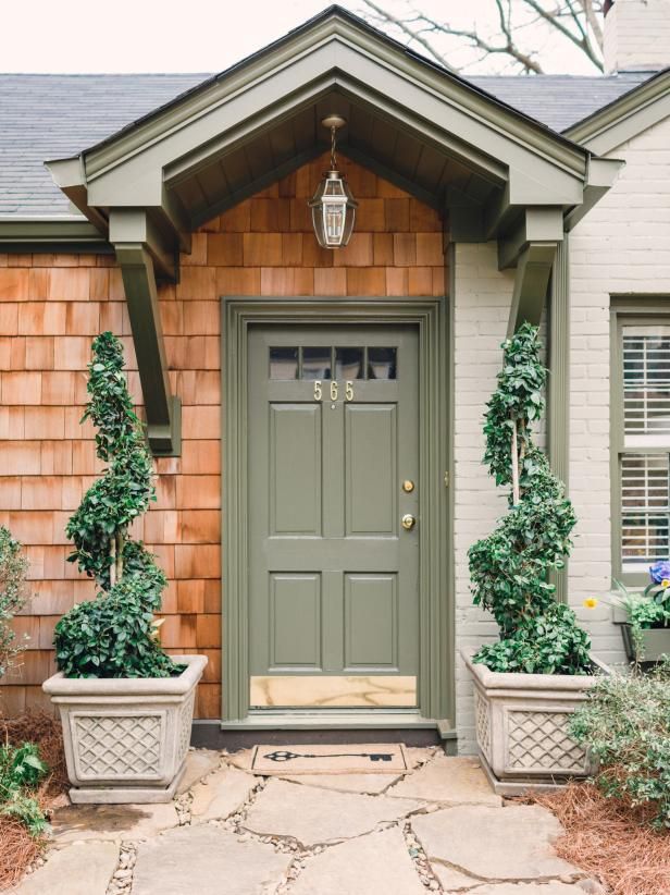 two planters on either side of the front door of a house with green doors