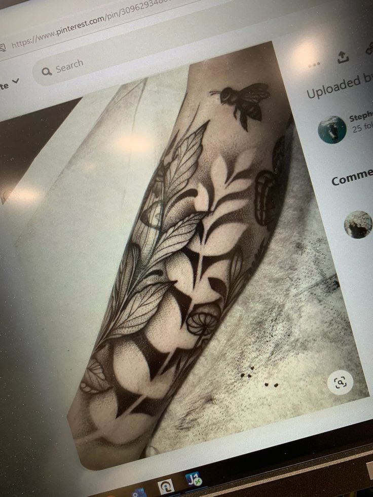 a black and white photo of a tattoo on someone's arm with flowers in it