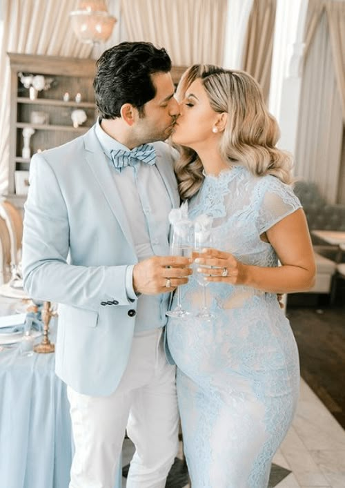 a man and woman kissing each other in front of a table with blue cloths