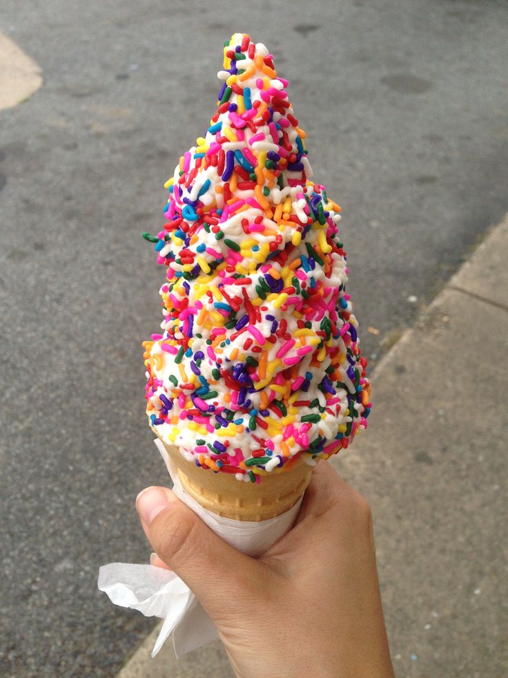 a hand holding up an ice cream cone with sprinkles on the top