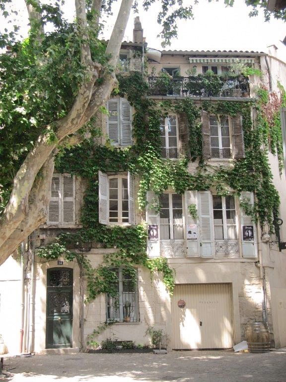 an old building with ivy growing all over it's windows and doors, along with a tree in front of it