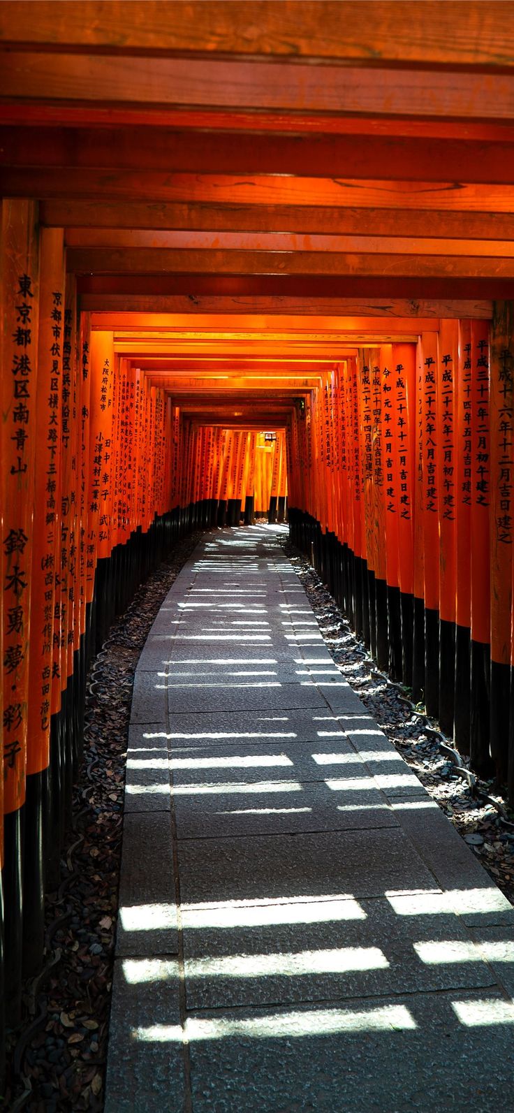 an alley lined with rows of orange and black torimika's in japan