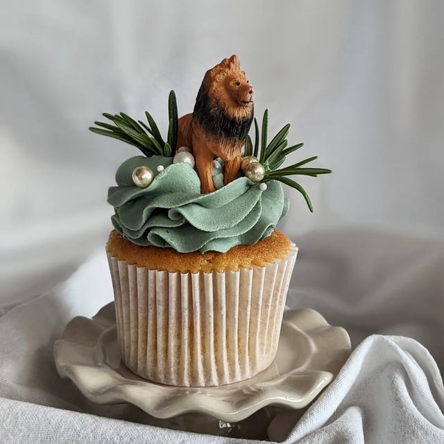 there is a cupcake decorated with a dog on top and greenery in the middle