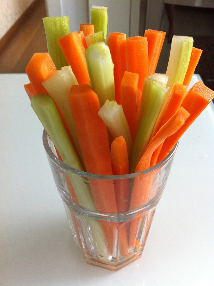 carrots and celery sticks in a clear glass cup on a white table