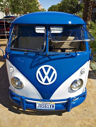 a blue and white vw bus parked in front of a building