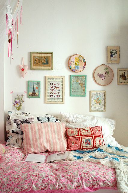 a bed covered in lots of pillows and pictures on the wall next to each other