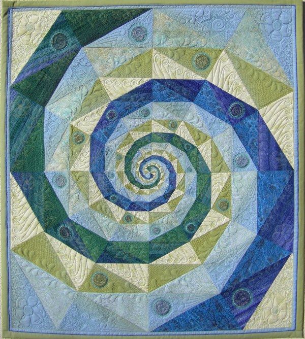 a blue and green quilted wall hanging with a spiral design on the center piece