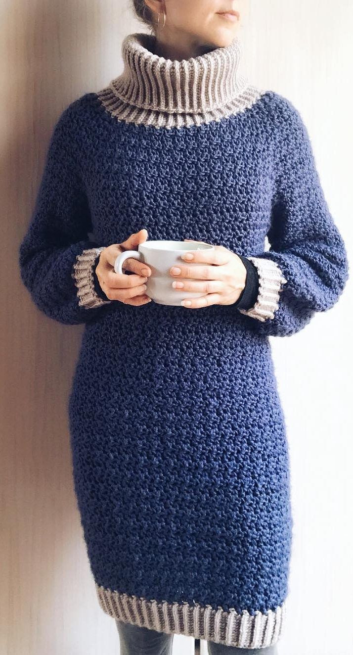 a woman is holding a cup and wearing a blue knitted dress with white stripes