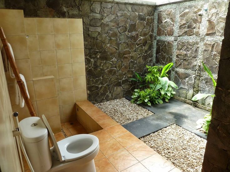 a bathroom with stone walls and flooring next to a planter filled with plants