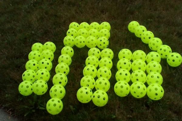 there are many yellow balls on the ground and one is in the shape of letters that spell out