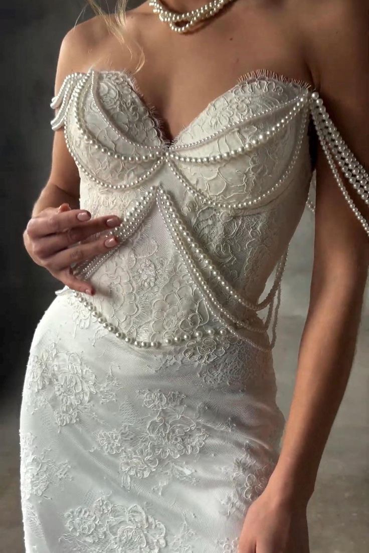 a woman in a wedding dress with pearls on her shoulder