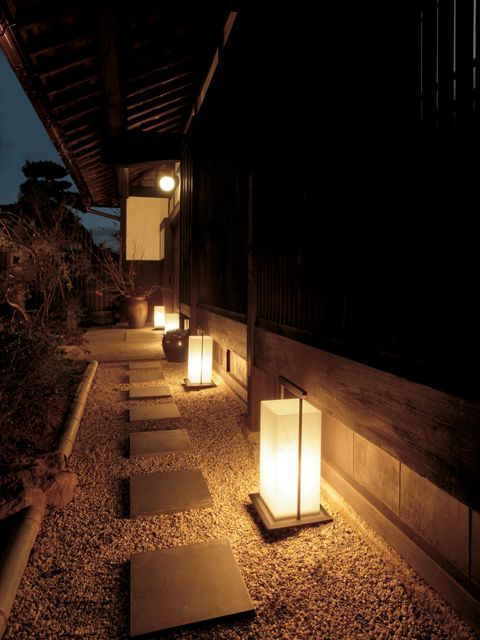 some lights that are on the side of a building in the night time, along with stones and gravel