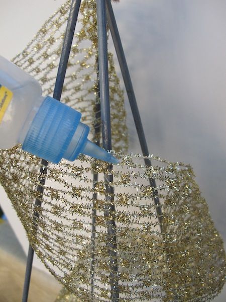 a plastic bottle is being used to decorate a christmas tree with tinsel and wire