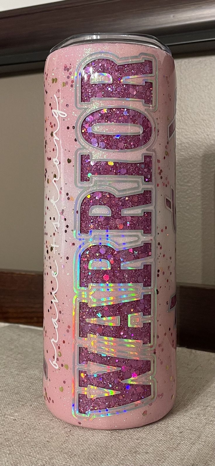 a pink can with glitter on it sitting on a table