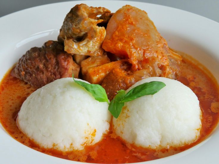 a white plate topped with meat and rice covered in sauce, garnished with green leaves