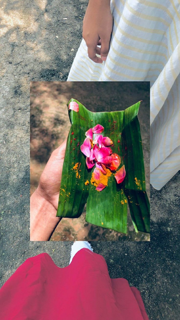 a person holding a banana with flowers in the center and another hand reaching for it