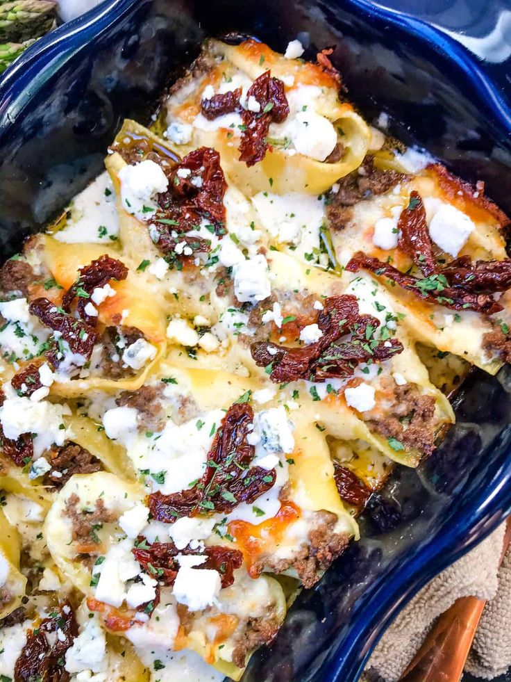 a casserole dish with meat, cheese and vegetables in it on a blue plate