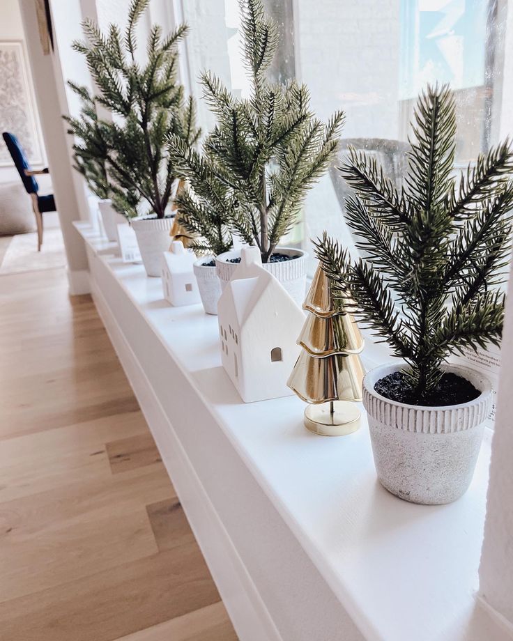 small christmas trees are lined up on a shelf in a room with white walls and wood floors