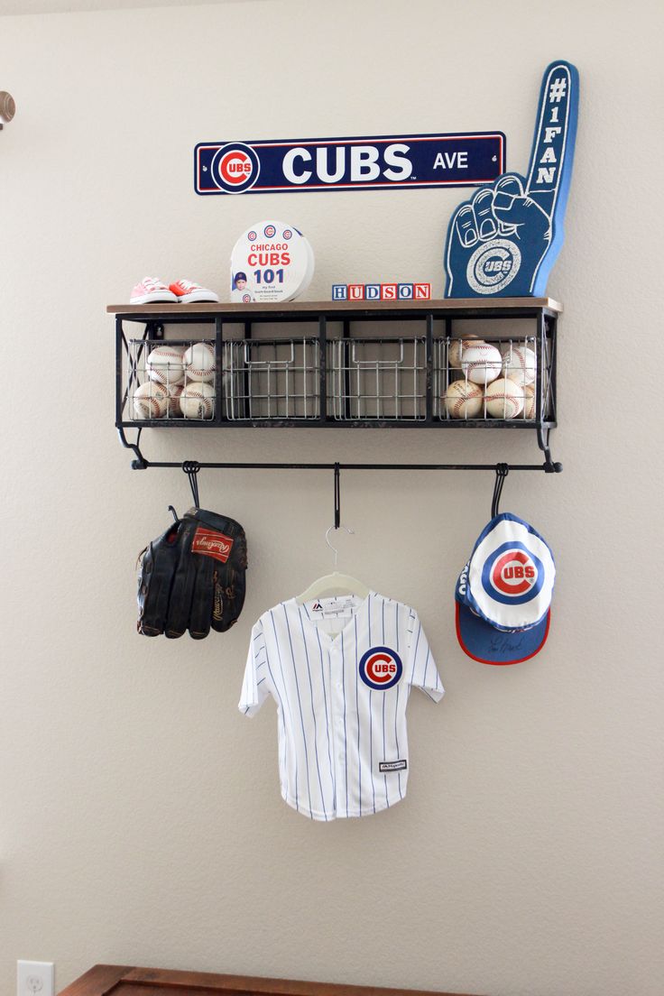 a baseball uniform hanging on a wall next to hats and glove rack with sports memorabilia