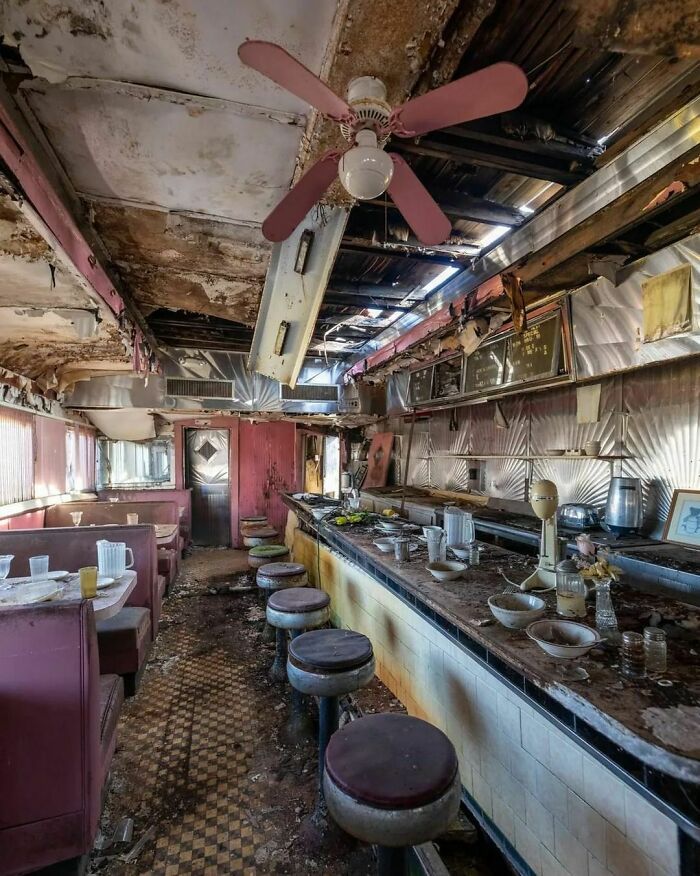 the inside of an abandoned restaurant with many tables and stools in front of it