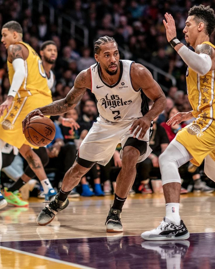 two basketball players in action on the court with people watching from the stands behind them