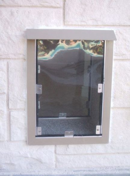 an open window on the side of a white brick building with water reflected in it