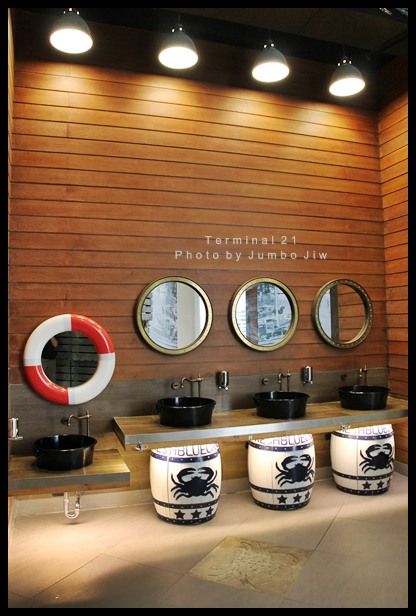 a bathroom with three sinks and mirrors on the wall next to two round mirrors above them