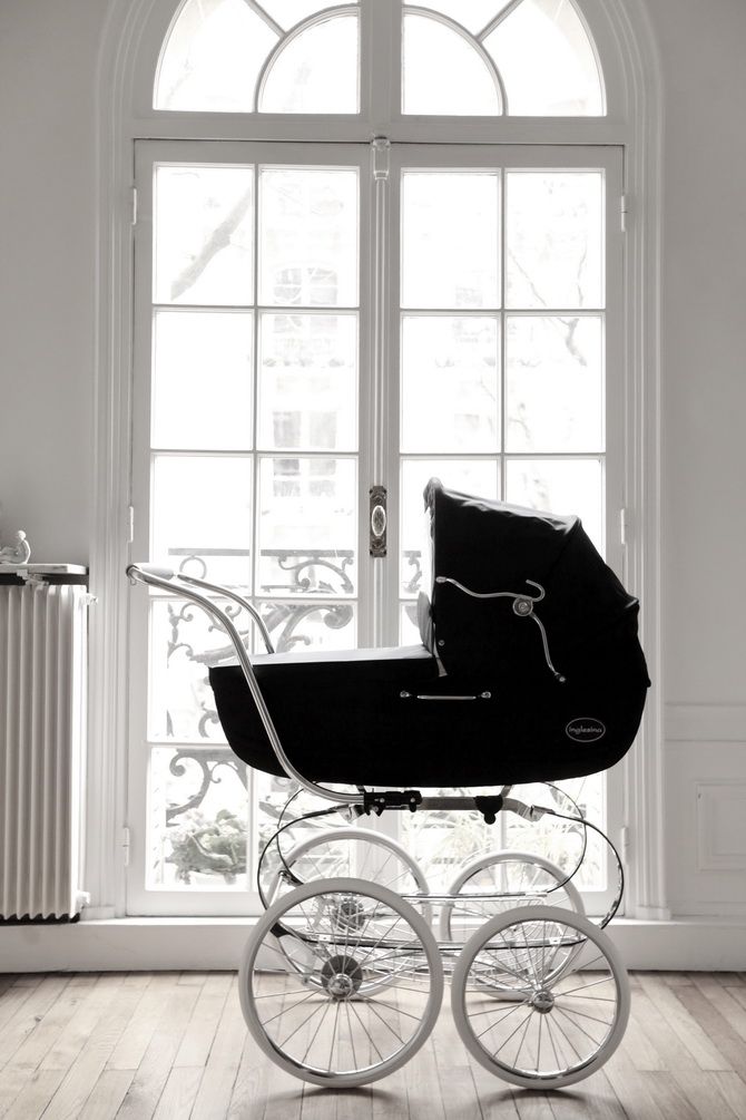 a black and white photo of a baby's carriage in front of a window