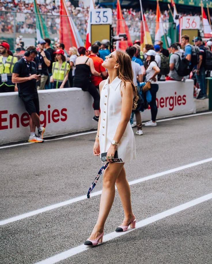 a woman walking down the street with a tennis racket in her hand and people watching