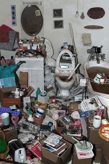 a cluttered room with many items on the floor, including a toilet and sink