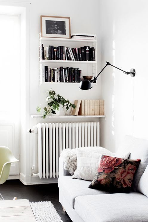 a living room filled with furniture and bookshelves next to a white radiator