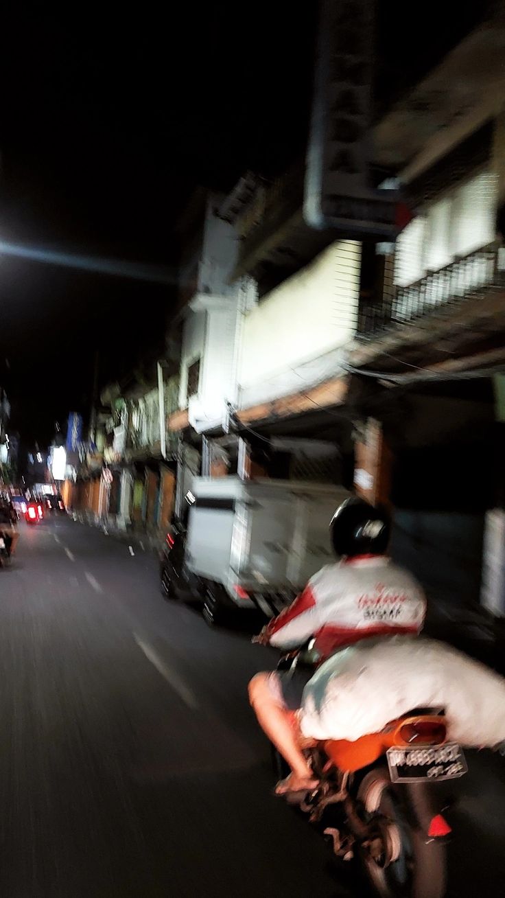 a man riding a motorcycle down a street at night