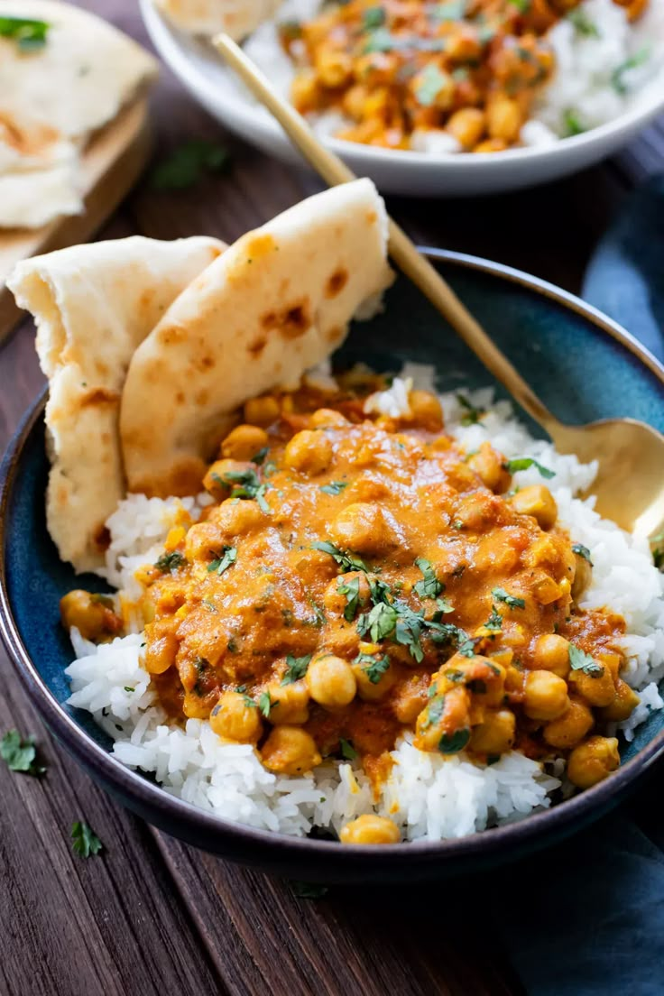 a bowl filled with rice and chickpeas next to pita bread on a wooden table