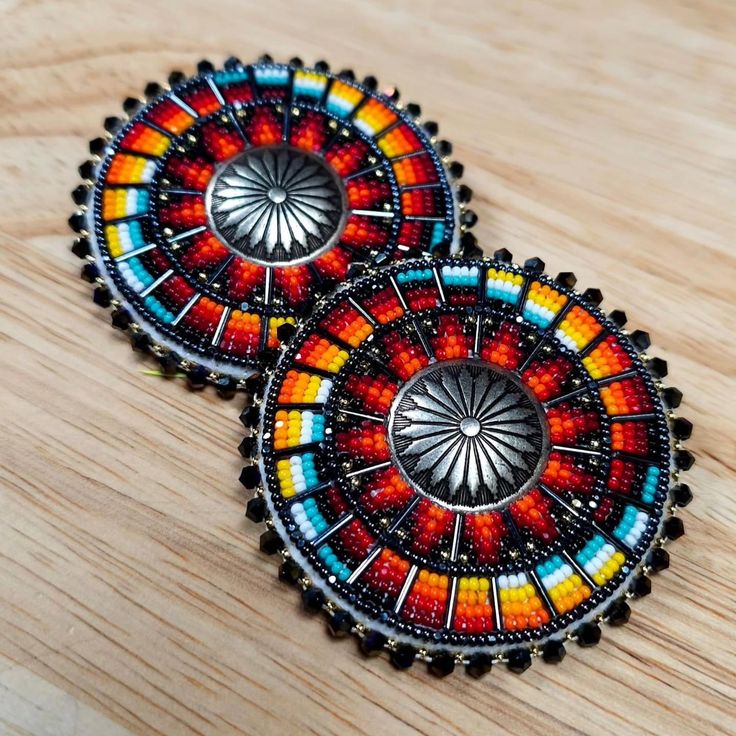 two colorful earrings sitting on top of a wooden table