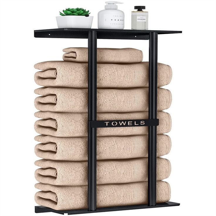 towels are stacked on top of each other in front of a shelf with two bottles